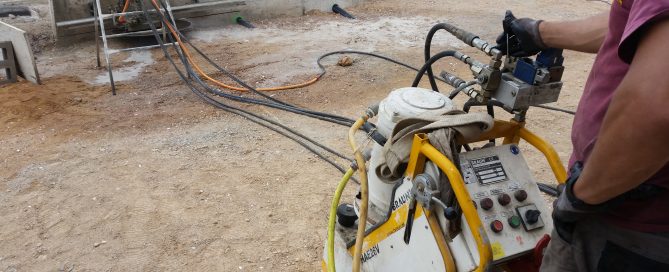 Tall de mur amb serra mural de disc de diamant i operari manejant-ho juntament amb l'equip elèctric hidràulic